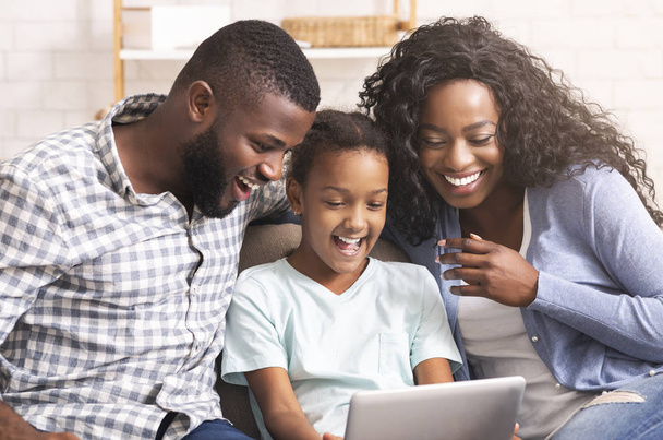 Negro familia viendo divertidos videos en digital tablet en casa
 - Foto, Imagen
