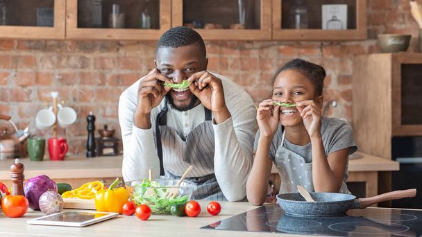 Vater und Tochter machen Schnurrbärte mit Salat - Foto, Bild