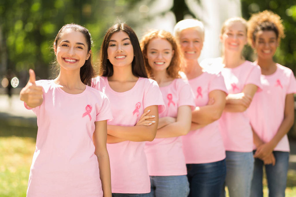 Добровольцы с раком молочной железы стоят в очереди, показывая пальчики на ногах в парке
 - Фото, изображение