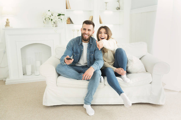 Happy couple watching Tv together, relaxing on sofa - Photo, Image