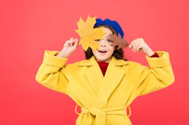 Enjoying autumn day. parisian girl child in french beret and yellow coat. fall season. fallen leaves bunch. school time. childhood happiness. happy little girl with maple leaf. autumn kid fashion - Foto, afbeelding
