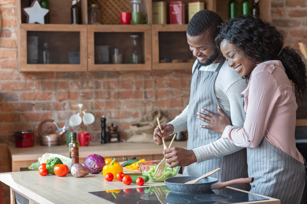 fröhliche schwarze Familie kocht gemeinsam Abendessen in Küche - Foto, Bild