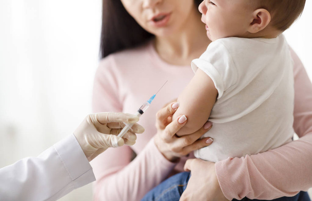 Lääkäri antaa lihaksensisäisen injektion pienelle vauvalle
 - Valokuva, kuva