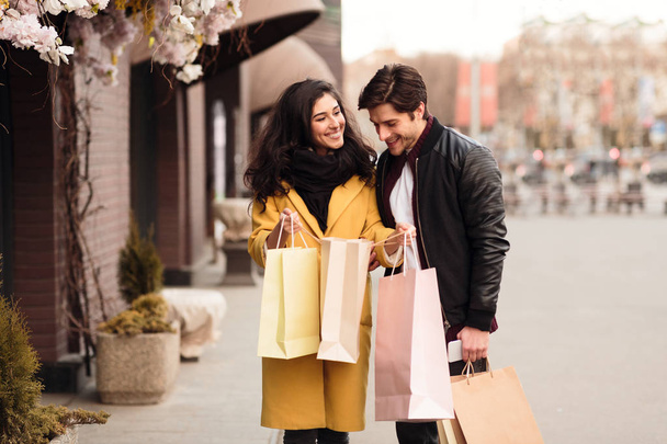 Frau zeigt Mann ihre Einkäufe, Mann schaut in Einkaufstasche - Foto, Bild
