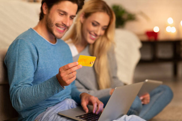 Millennial puolisot ostoksia verkossa käyttäen kannettavaa tietokonetta ja luottokorttia sisätiloissa
 - Valokuva, kuva