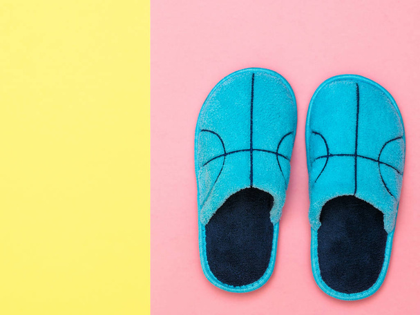 A pair of blue Slippers on a pink background next to a yellow background. The view from the top. Flat lay. - Photo, Image
