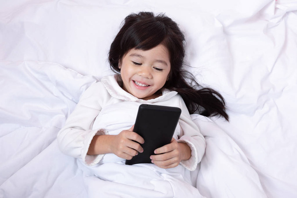 Top näkymä Aasian pieni lapsi hauskaa pelaa älypuhelin makaa
  - Valokuva, kuva