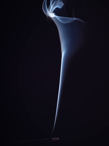 Ароматична паличка, що розгладжується білим димом, ізольована на чорному тлі, крупним планом. Абстрактний фон палаючого ладану, ефект пензля. Східний аромат для медитації та релаксації
. - Фото, зображення
