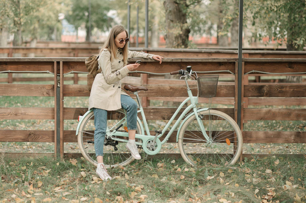 Girl looking in her phone sitting on bike - Фото, изображение