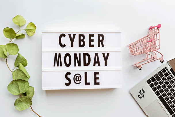 Creative promotion composition Cyber monday sale text on lightbox on white background, next grocery trolley, laptop. Flat lay, top view, overhead, mockup - Foto, afbeelding