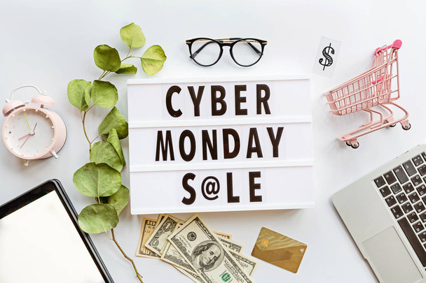 Creative promotion composition Cyber monday sale text on lightbox on white background, next grocery trolley, alarm clock, laptop, tablet. Banner for web design. Flat lay, top view, overhead, mockup - Foto, imagen