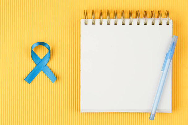 cinta de próstata azul en cuaderno abierto aislado sobre fondo amarillo
 - Foto, imagen