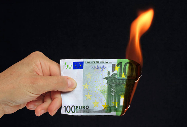 El siyah arka plan recto verso üzerinde kavramsal resim yanan 100 € banka notu tutan - Fotoğraf, Görsel