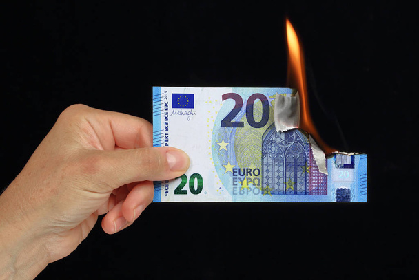 Mão segurando uma nota bancária de 20 euros queimando imagem conceitual em fundo preto recto verso
 - Foto, Imagem
