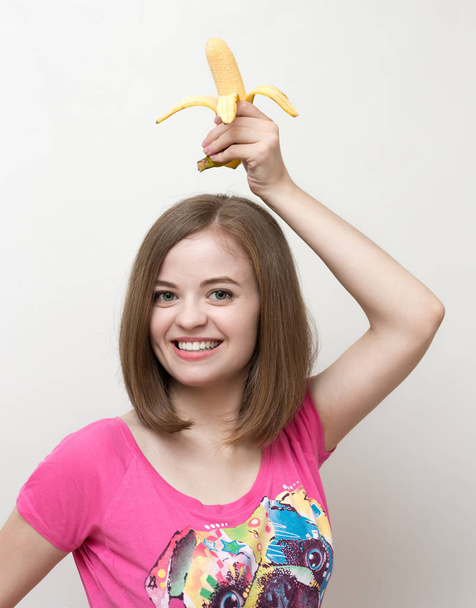 Retrato de una mujer caucásica sonriente con plátano amarillo en la mano. Estilo de vida saludable, dieta vegetariana de frutas
. - Foto, imagen