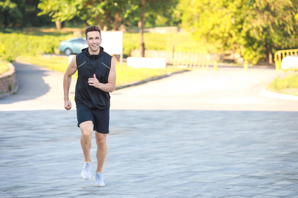 Sporty young man running outdoors - Photo, image