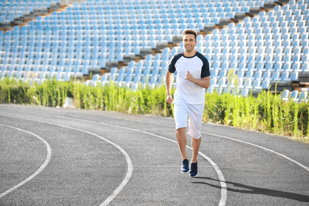 Sporty young man running at the stadium - Fotoğraf, Görsel