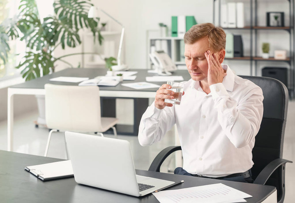 Портрет бизнесмена с напряженной питьевой водой в офисе
 - Фото, изображение