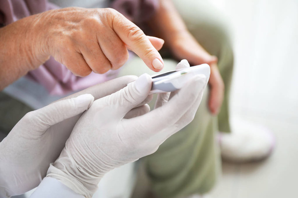 Doctor checking blood sugar level of diabetic woman at home, closeup - Photo, Image