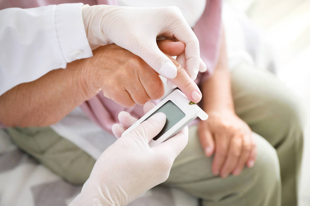 Medico controllando i livelli di zucchero nel sangue della donna diabetica a casa, primo piano
 - Foto, immagini