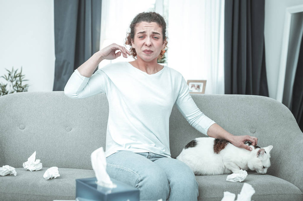 Woman wearing jeans sneezing having intolerance to cats - Photo, Image