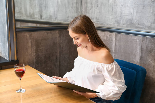 Jeune femme avec menu assis au restaurant
 - Photo, image