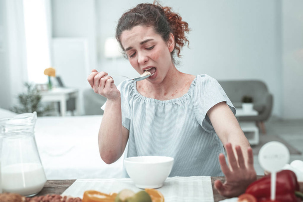 Woman with rash over all body having breakfast full of allergens - Foto, afbeelding
