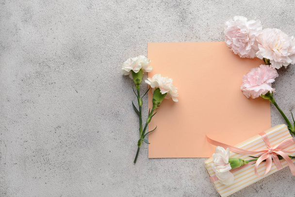 Üdvözlőkártya gyönyörű szegfű virágok és díszdobozban a szürke háttér - Fotó, kép