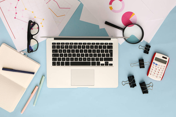 moderner Laptop mit Taschenrechner, Dokumenten und Schreibwaren auf farbigem Hintergrund - Foto, Bild