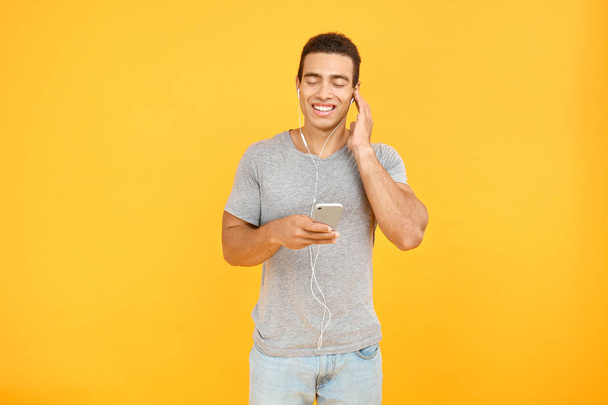 Hombre afroamericano guapo escuchando música sobre fondo de color
 - Foto, imagen