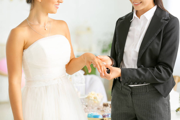 Young lesbian couple exchanging rings during wedding ceremony - Foto, Imagen