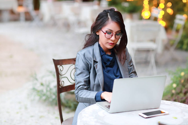 niedliche und charmante Geschäftsfrau mit Brille, die am Laptop aus dem Restaurant oder Café arbeitet - Foto, Bild