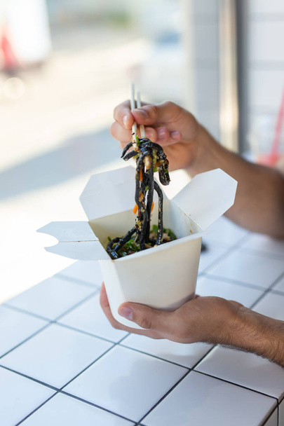 Lähikuva mies syö kiinalaisia nuudeleita kahvilassa. Käsite terveellistä aasialaista ruokaa
. - Valokuva, kuva