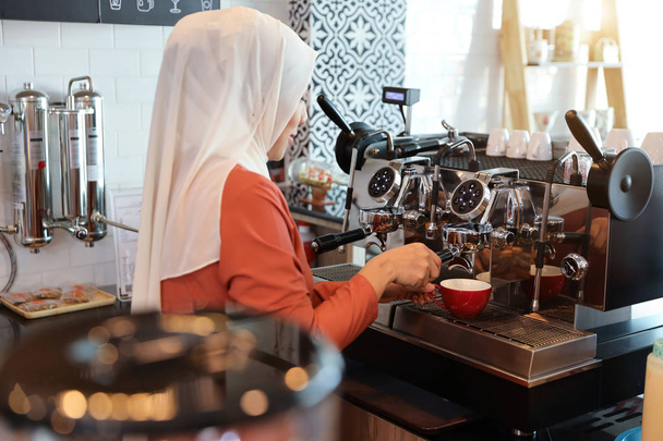 молодая мусульманская бариста делает кофе
 - Фото, изображение