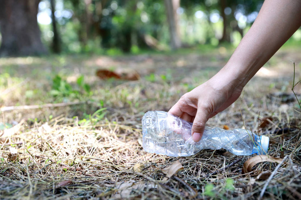 Voluntário mão turística é limpar lixo e detritos de plástico na floresta suja, recolhendo-os em grande saco azul
 - Foto, Imagem