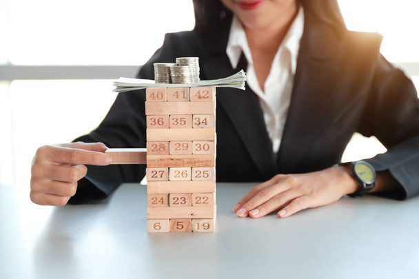 Empresária jogando jogo de bloco de madeira com dinheiro e moeda, ideia de conceito de estratégia de gestão
 - Foto, Imagem