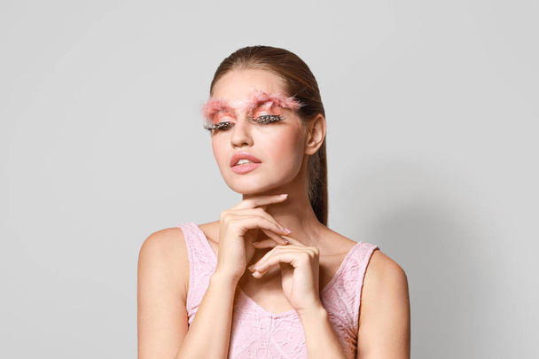junge Frau mit kreativen Wimpern und Augenbrauen auf grauem Hintergrund - Foto, Bild