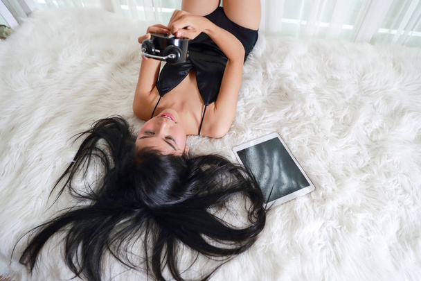 belle et sexy femme couchée sur le lit avec tablette et réveil d'installation
 - Photo, image