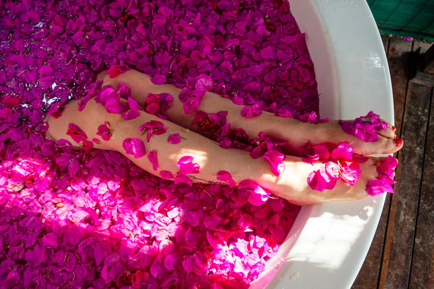 cropped shot of barefoot woman with flowers, candles, colorful sea salt and bath for nails in beauty salon in hotel - 写真・画像