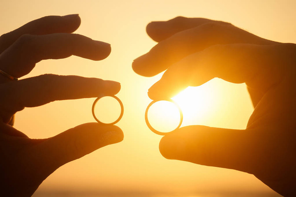 Two wedding rings on coral in front of the seaside at sunset - Foto, Imagem