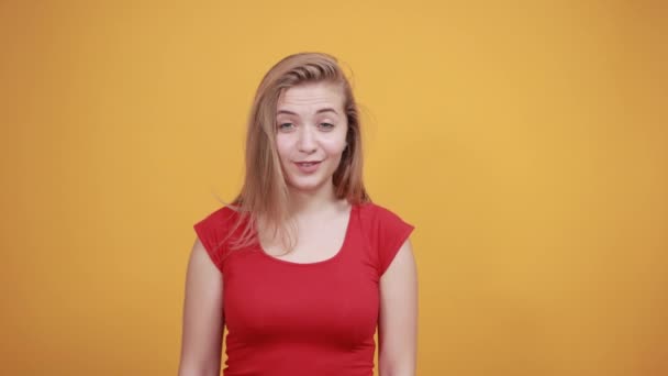 jeune fille blonde en t-shirt rouge sur fond orange isolé montre des émotions
 - Séquence, vidéo
