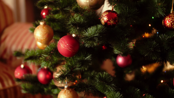 4k-video van camera langzaam bewegen en pannen over kleurrijke gloeiende lichten en kerstballen op Christmas Tree in de woonkamer - Video
