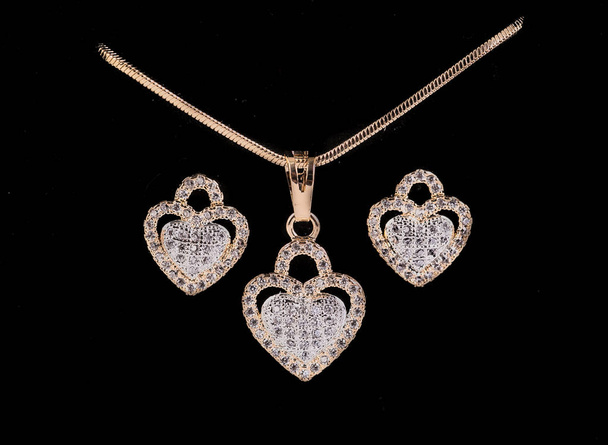 Boucles d'oreilles et pendentifs en diamant en forme de coeur sur le sol noir
. - Photo, image