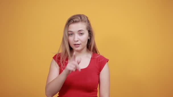 izole turuncu arka plan üzerinde kırmızı t-shirt genç sarışın kız duygularını gösterir - Video, Çekim