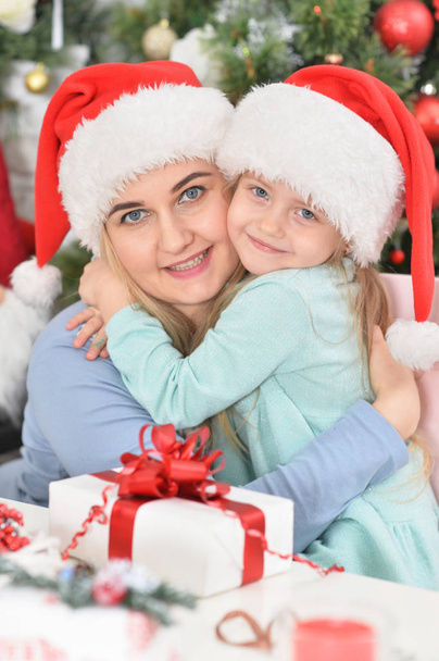 Portrait of little girl with her mother in Santa hats  - Fotoğraf, Görsel