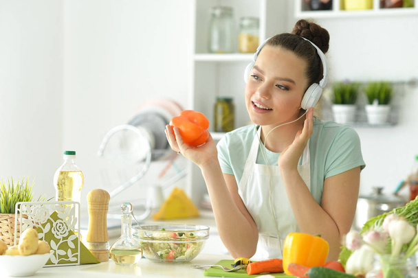 beautiful young woman making  salad  and listening to music  - 写真・画像
