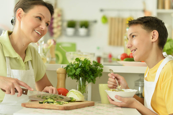 Mother and son eating fresh salad at kitchen - Foto, Imagen