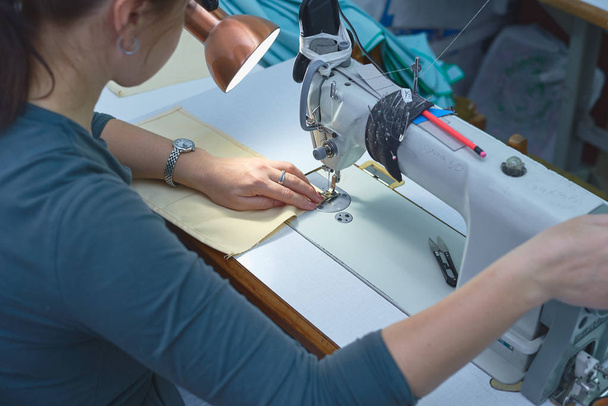 Una mujer cose en una máquina de coser eléctrica
. - Foto, imagen