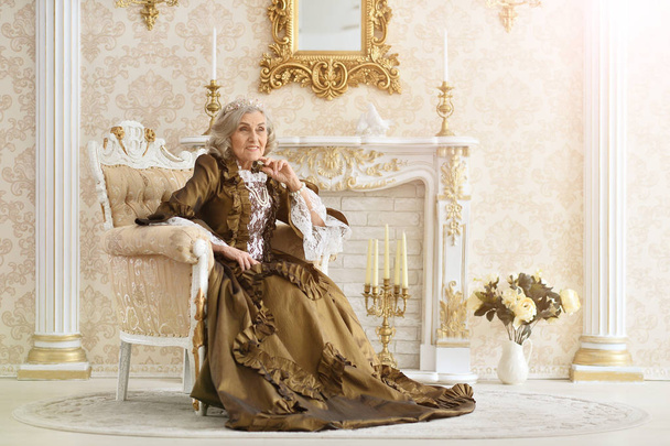 beautiful senior woman Queen sitting in armchair - Photo, image