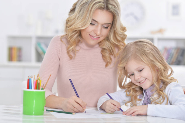 little cute girl with mother drawing at the table at home - Photo, image